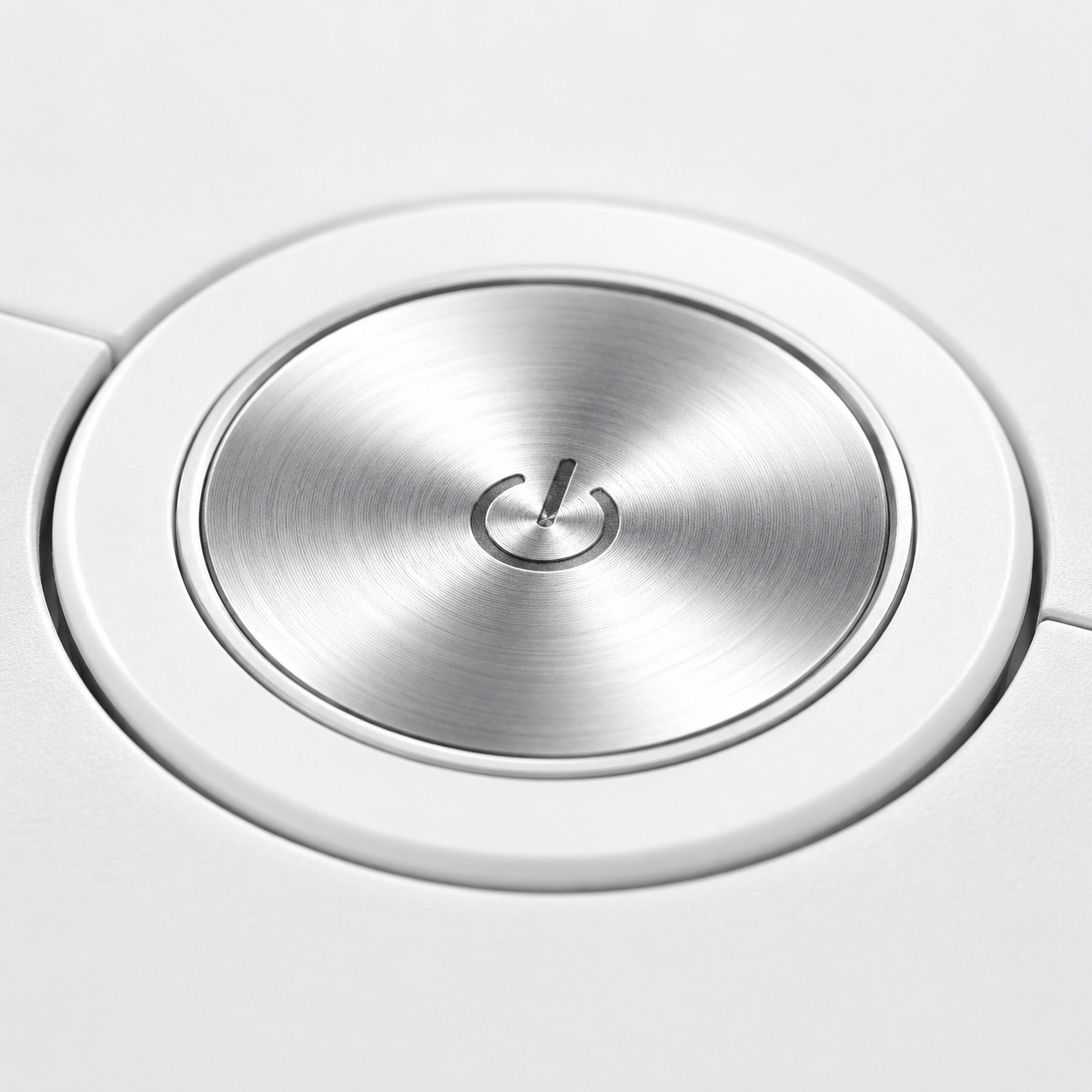 Close-up of the robot vacuum cleaner's premium metallic power button on a white body, featuring a brushed aluminum finish and minimalist one-touch control design.