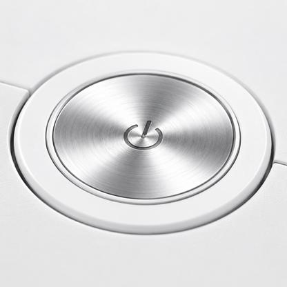Close-up of the robot vacuum cleaner's premium metallic power button on a white body, featuring a brushed aluminum finish and minimalist one-touch control design.