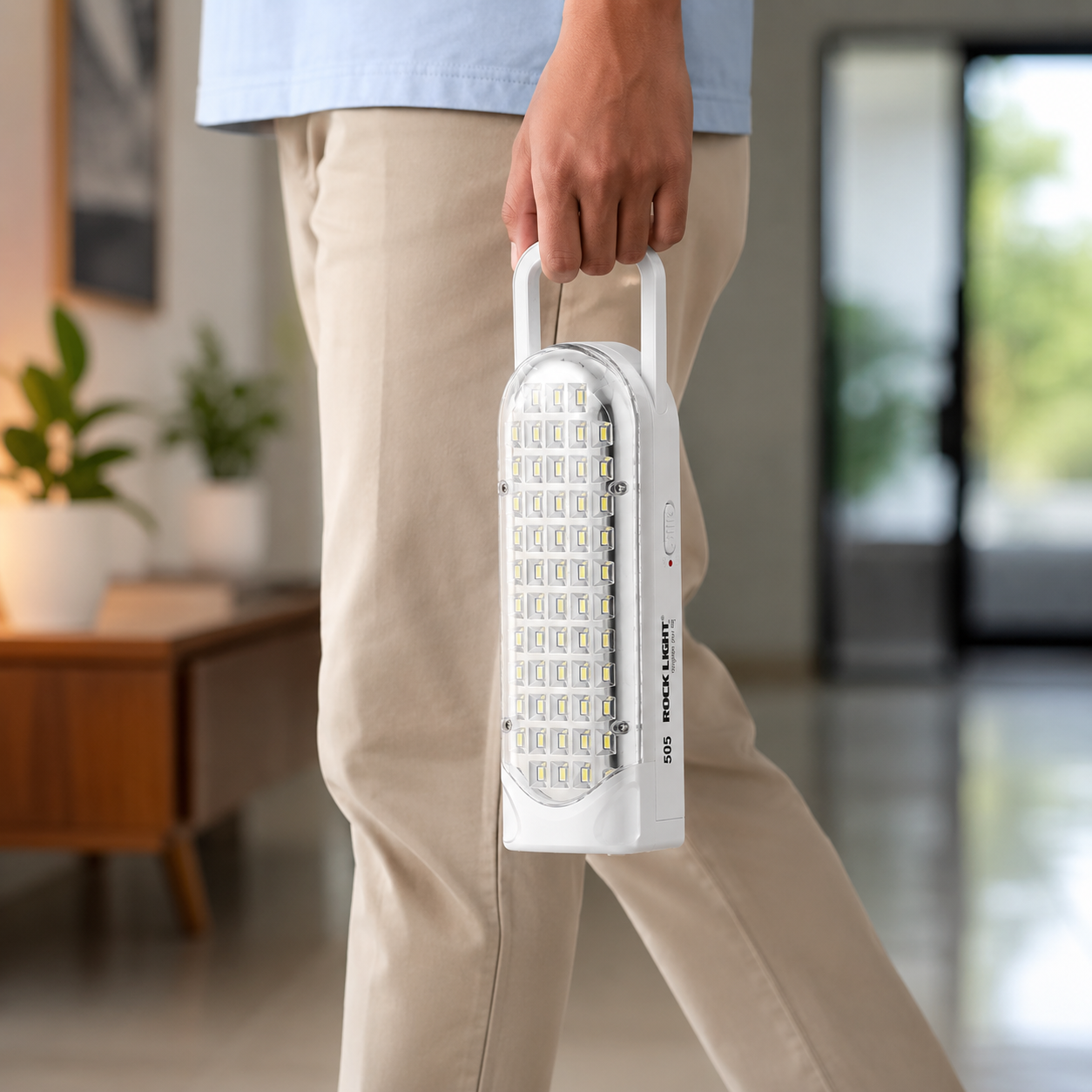 Person carrying a rechargeable 56 SMD LED emergency light by its built-in handle, highlighting its lightweight portable design for home, travel, camping, and emergency use.