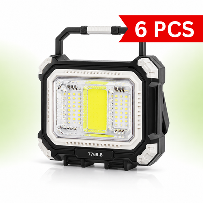 Front view of the 7769-B rechargeable solar camping light featuring a rugged black and white ABS body, ultra-bright central COB floodlight, dual LED side panels, foldable carry handle, and portable toolbox-inspired design