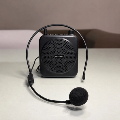 Portable wireless voice amplifier with adjustable headset microphone displayed on a clean surface, featuring a compact black design, clear sound output, rechargeable battery, and hands-free operation for teachers and trainers.