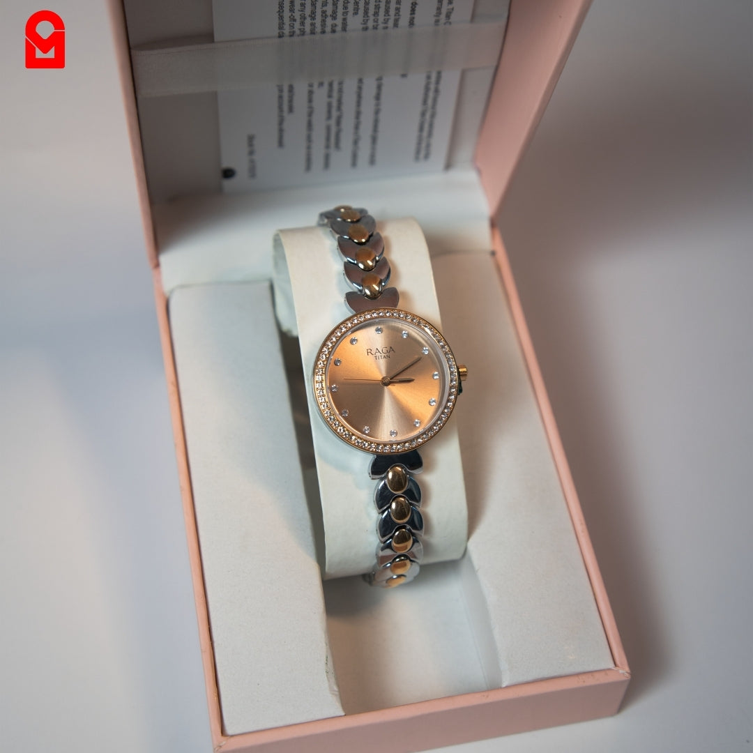 Analog bracelet watch with rose gold dial and stainless steel strap shown in packaging.