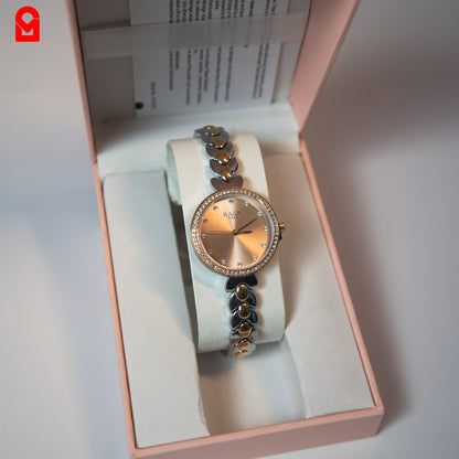 Analog bracelet watch with rose gold dial and stainless steel strap shown in packaging.