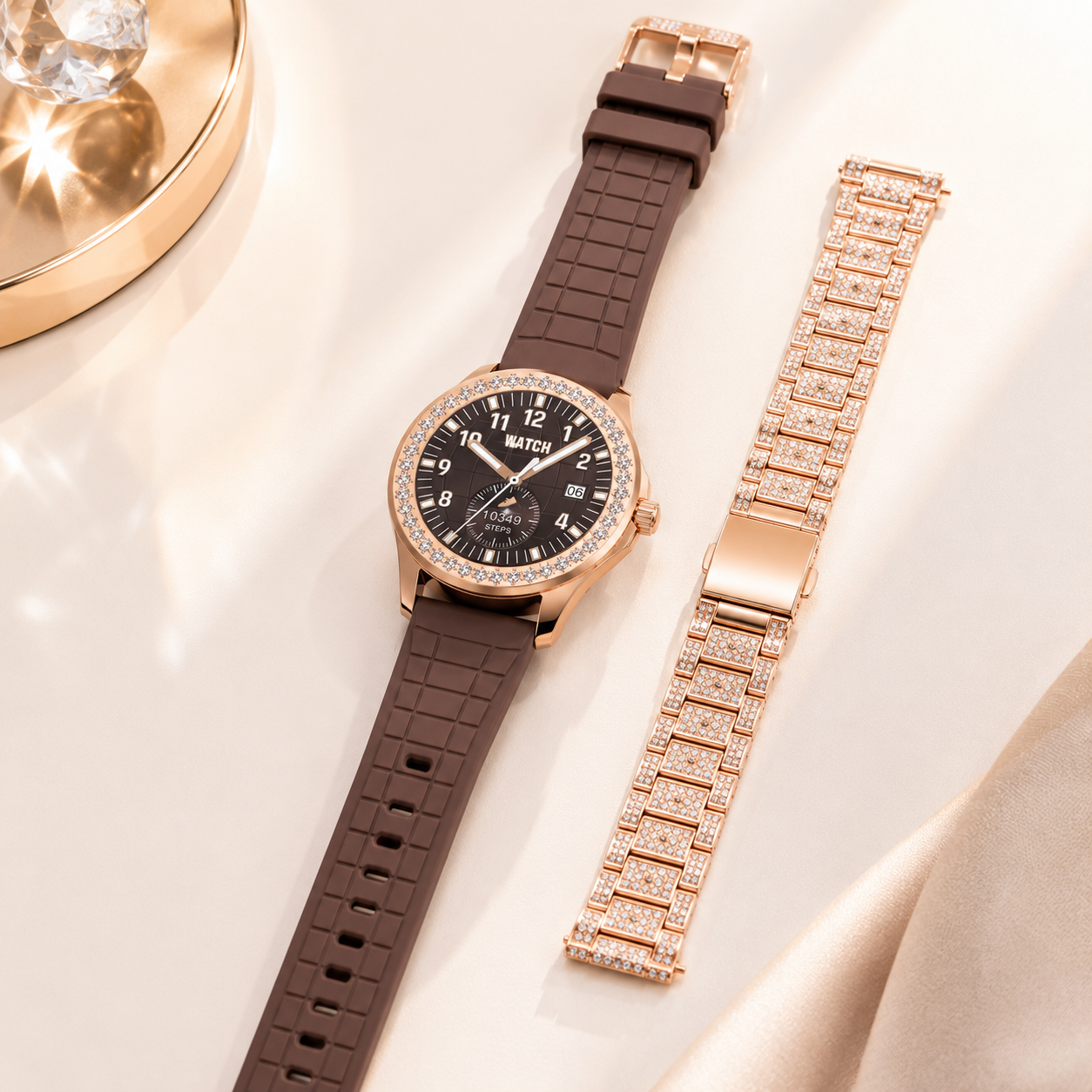 Luxury round smartwatch with brown silicone strap and interchangeable crystal-studded metal bracelet displayed on a premium marble surface, highlighting the included dual strap design