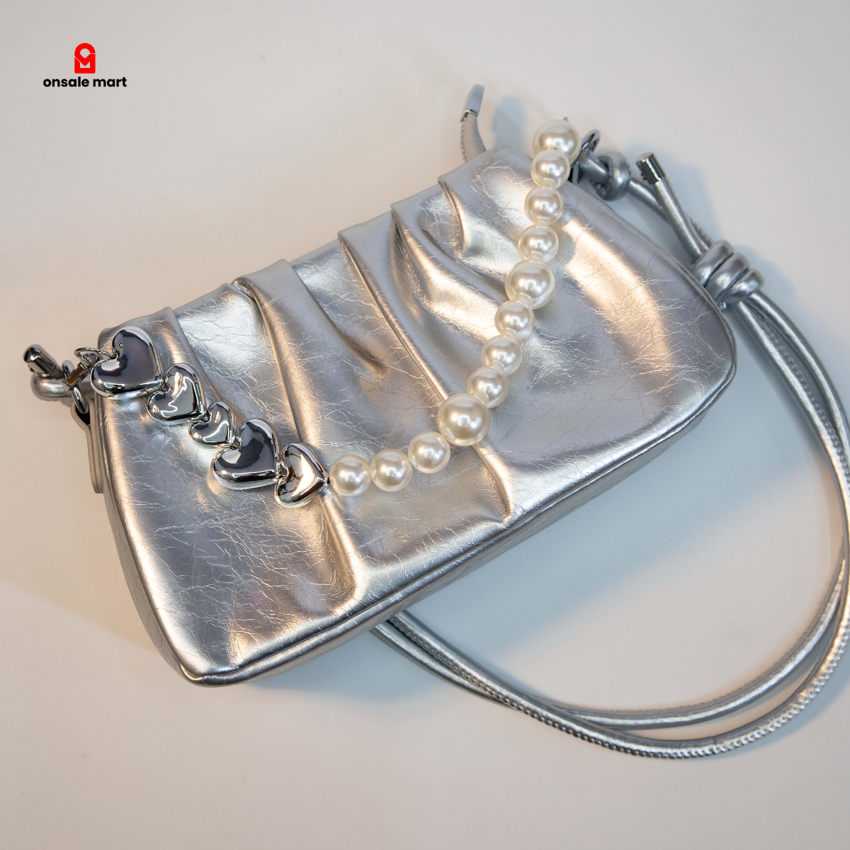 Metallic silver ruched bag showing pearl and heart chain detail.