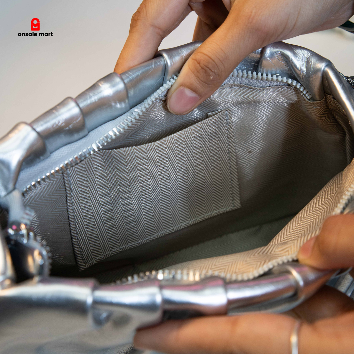 Interior view of silver ruched bag with zip pocket and fabric lining.
