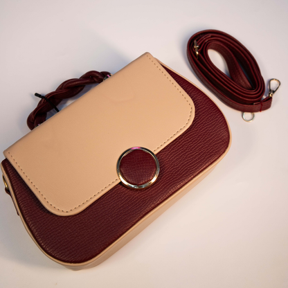 Women’s maroon sling bag with detachable strap and braided handle design.