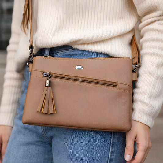 Tan zip closure crossbody sling bag worn with casual outfit.
