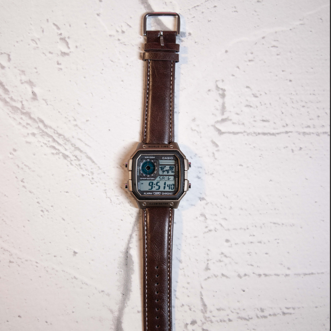 Vintage Brown Digital Square Watch with retro digital display and brown leather strap on marble background