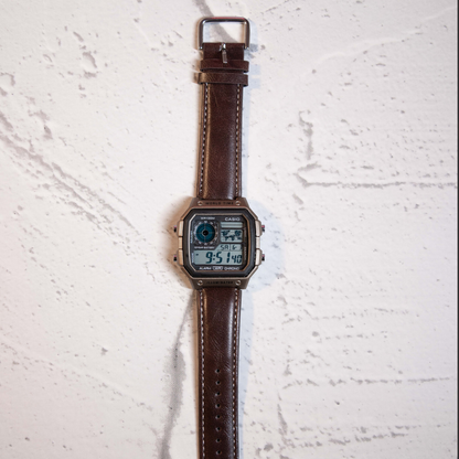 Vintage Brown Digital Square Watch with retro digital display and brown leather strap on marble background