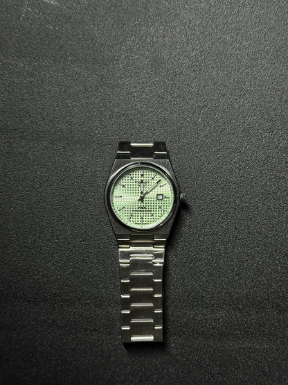 Replica watch with textured light green waffle dial, stainless steel integrated strap, date display and modern luxury sports watch styling