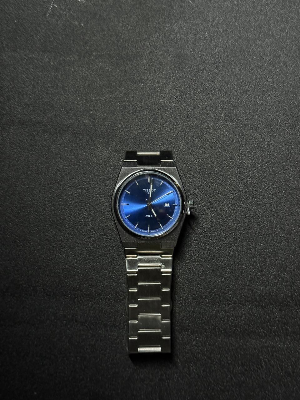 Blue dial replica watch featuring stainless steel bracelet, minimalist analog display, date function and premium luxury-inspired wristwatch design