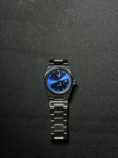 Blue dial replica watch featuring stainless steel bracelet, minimalist analog display, date function and premium luxury-inspired wristwatch design