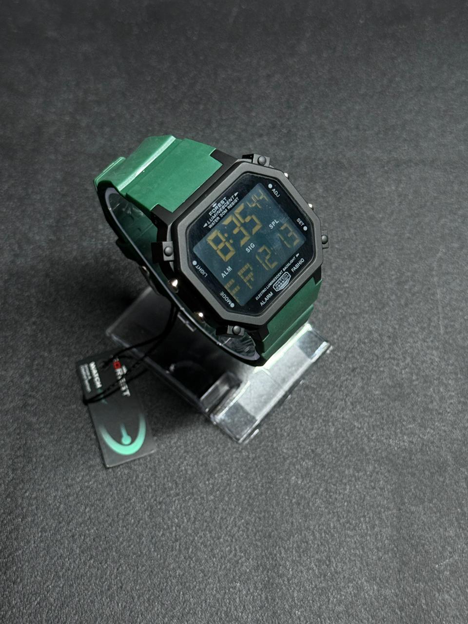 Replica digital sports watch with green silicone strap, octagonal black dial, LED display, alarm and stopwatch functions on display stand