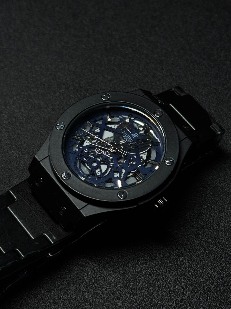 Replica watch with blue skeleton dial, black stainless steel bracelet, luxury open-work design, men's fashion wristwatch on dark background