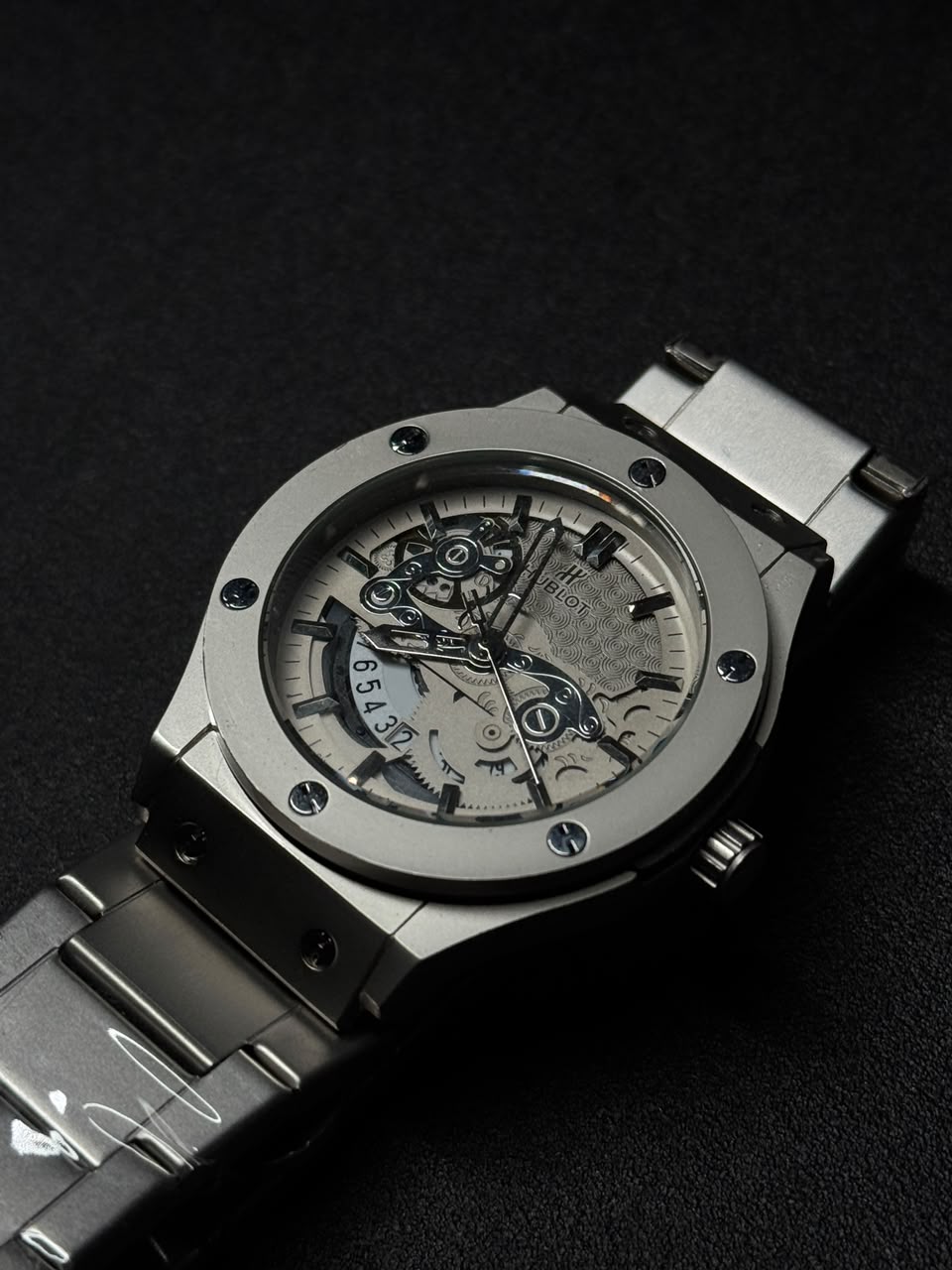 Luxury silver skeleton dial replica watch with stainless steel bracelet, transparent mechanical-style face and premium sports watch design.