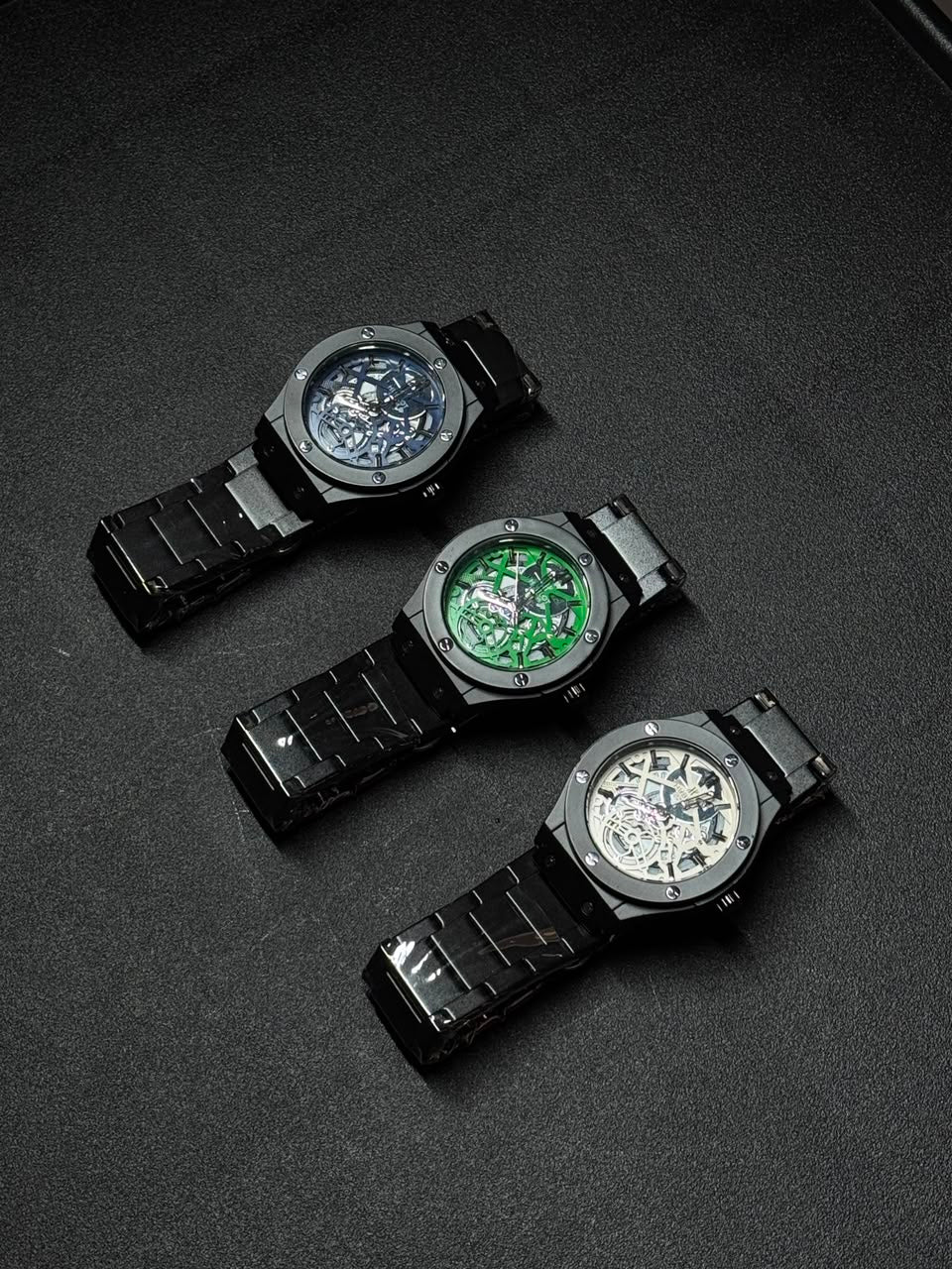 Replica watch collection with blue, green and white skeleton dials, black stainless steel bracelets, luxury-inspired men's watches
