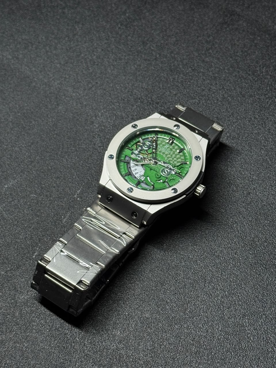 Green skeleton dial replica watch with stainless steel bracelet, luxury sports design and detailed mechanical-style display.