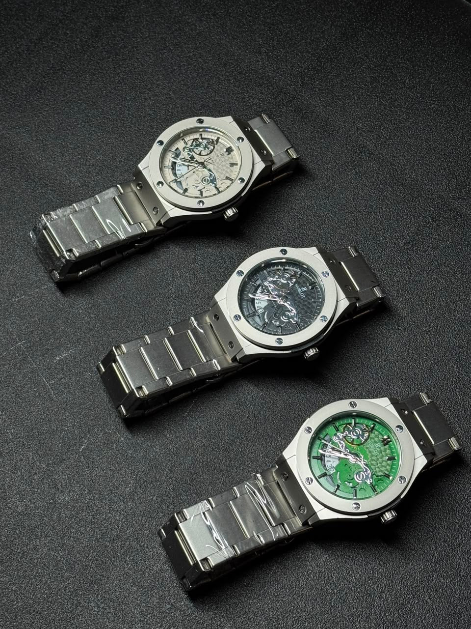 Replica watch collection featuring silver, black and green skeleton dial watches with stainless steel bracelets and luxury-inspired design.