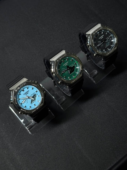 Collection of replica watches featuring sky blue, green and black dials with octagonal bezels and black straps displayed in premium studio lighting.