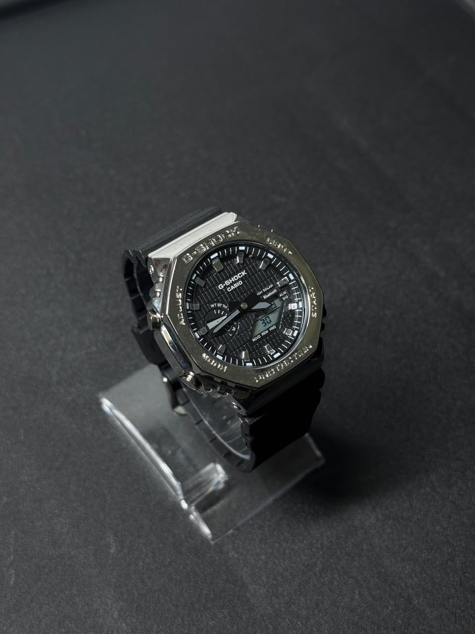 Black dial replica watch with analog digital display, octagonal bezel and black resin strap showcased on a dark studio background.