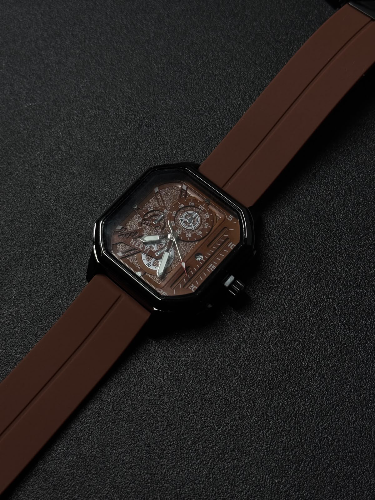 Brown silicone strap replica watch close-up showing square black case, textured skeleton dial, and premium fashion timepiece details.