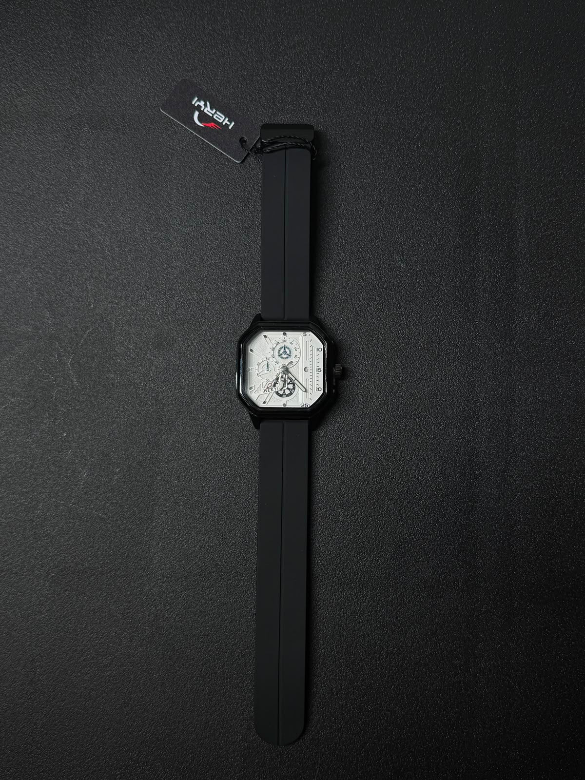 Black silicone strap replica watch featuring square black case, white skeleton dial, and modern luxury-inspired design.