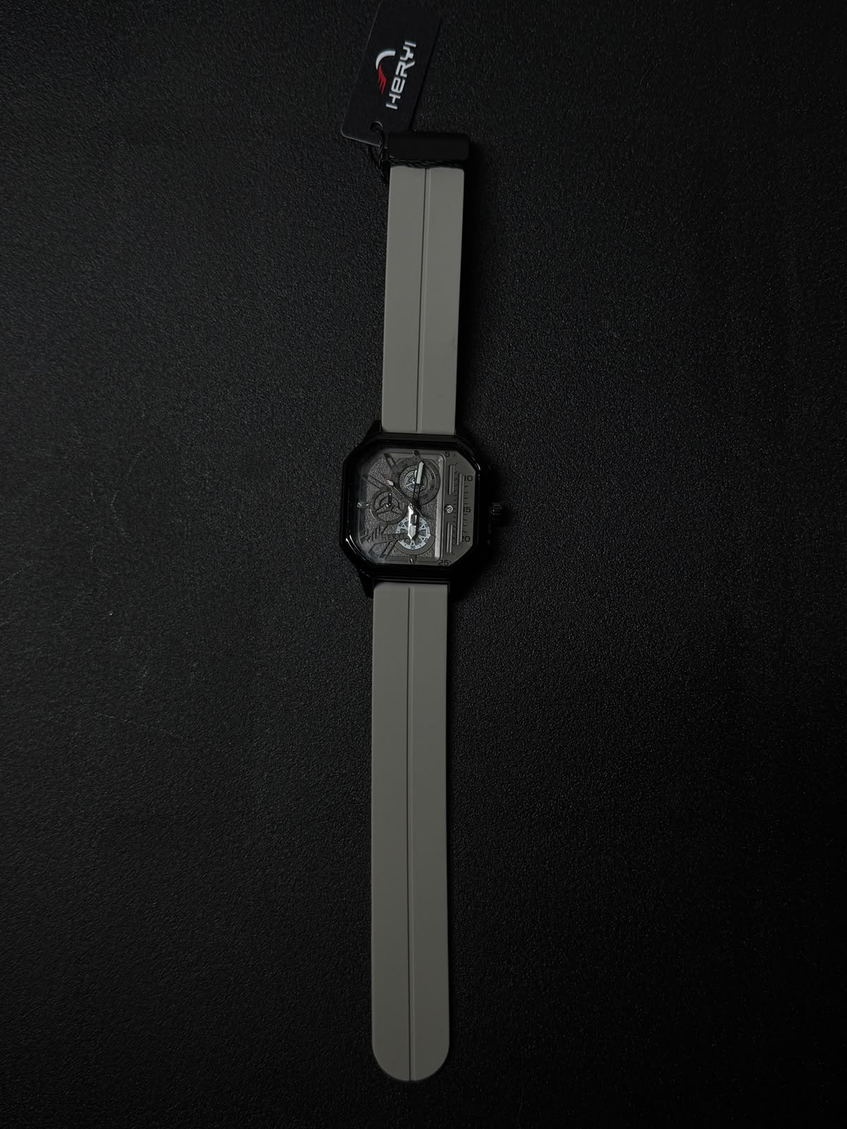 Grey silicone strap replica watch with black square case and detailed multi-layer skeleton style dial, luxury-inspired fashion timepiece.