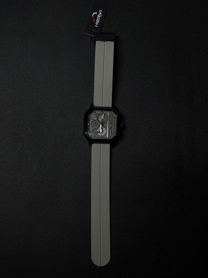 Grey silicone strap replica watch with black square case and detailed multi-layer skeleton style dial, luxury-inspired fashion timepiece.
