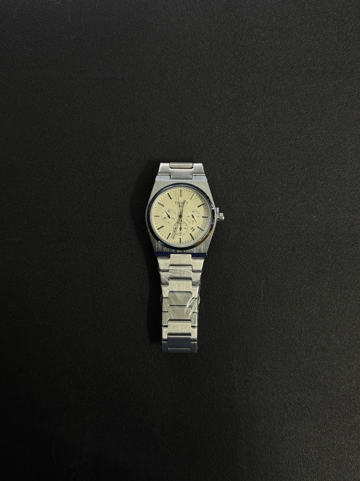 Silver stainless steel replica watch featuring a textured white dial, integrated bracelet and elegant minimalist luxury design.