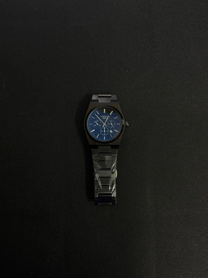 Black replica watch with blue dial, integrated metal bracelet and modern luxury chronograph-inspired styling.
