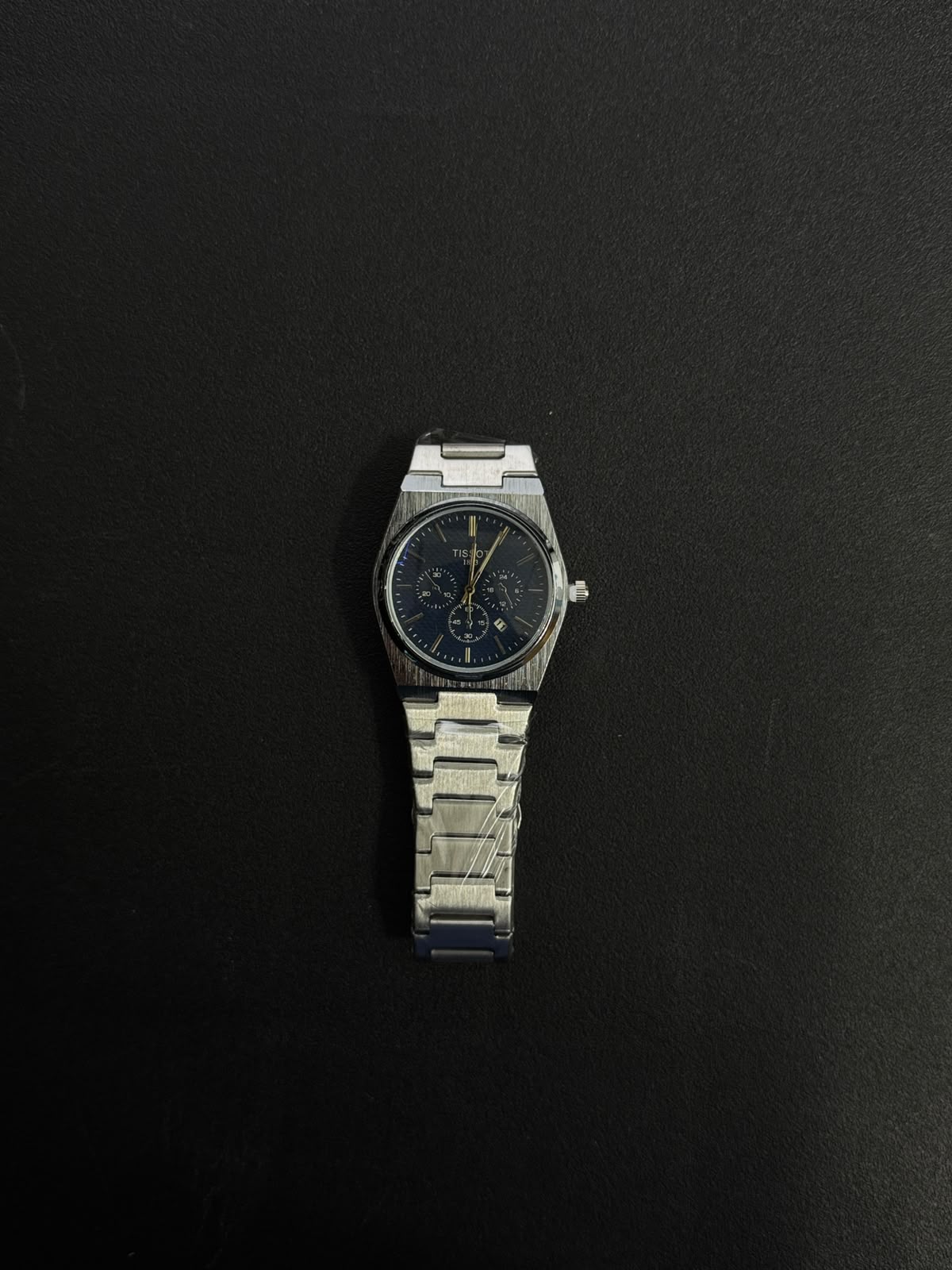 Silver stainless steel replica watch with blue chronograph-style dial, integrated bracelet and premium luxury sports watch design.