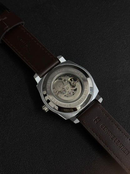 Automatic-style replica watch back view featuring transparent exhibition case back and brown leather strap on black background