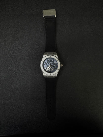 Hublot-inspired replica watch with silver case, blue open-work dial, black strap, and luxury skeleton movement design full view