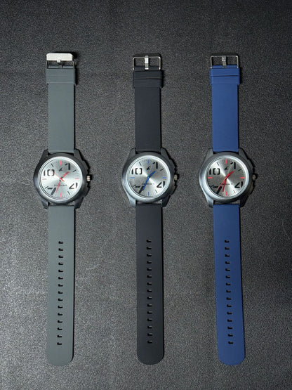 Replica Watch collection with grey, black and blue silicone strap options, silver sunburst dial, black case and contemporary men's analog watch design.