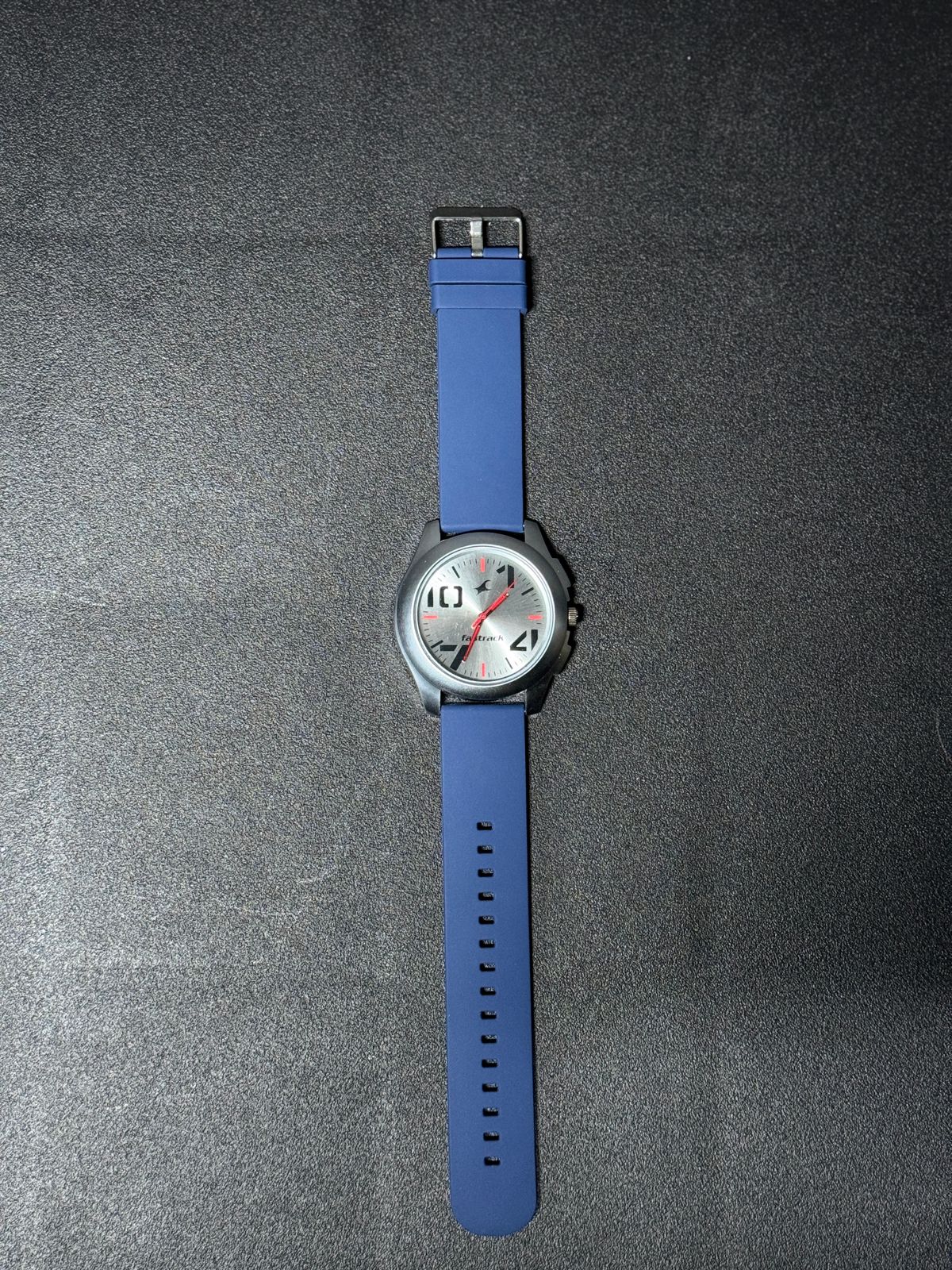 Replica Watch featuring blue silicone strap, silver brushed dial, black round case and red accent hands, stylish men's everyday analog wristwatch.