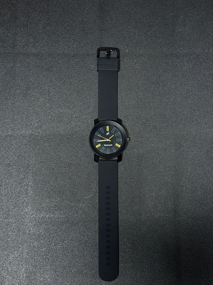 Replica watch with black silicone strap, black round dial, yellow accent markers and sleek minimalist analog design on dark background