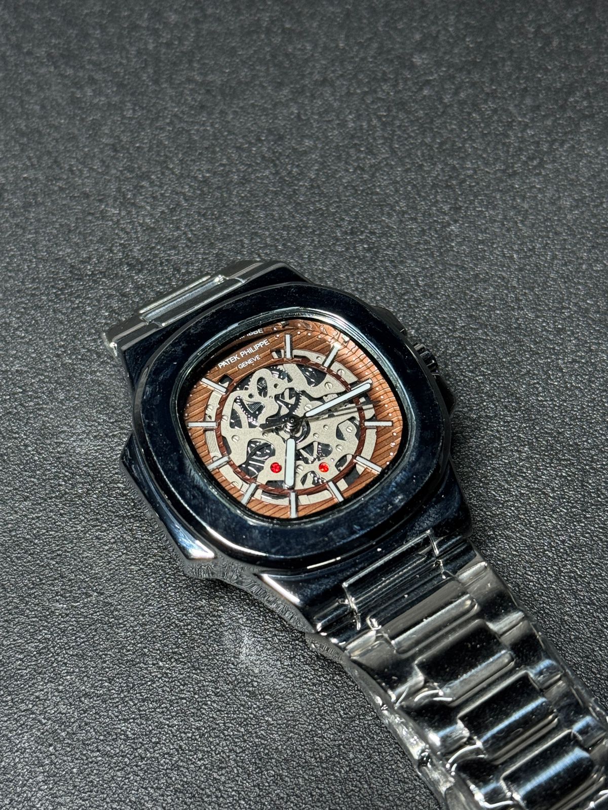 Replica watch with brown skeleton dial, stainless steel bracelet, luxury automatic-style design, black bezel wristwatch product photography