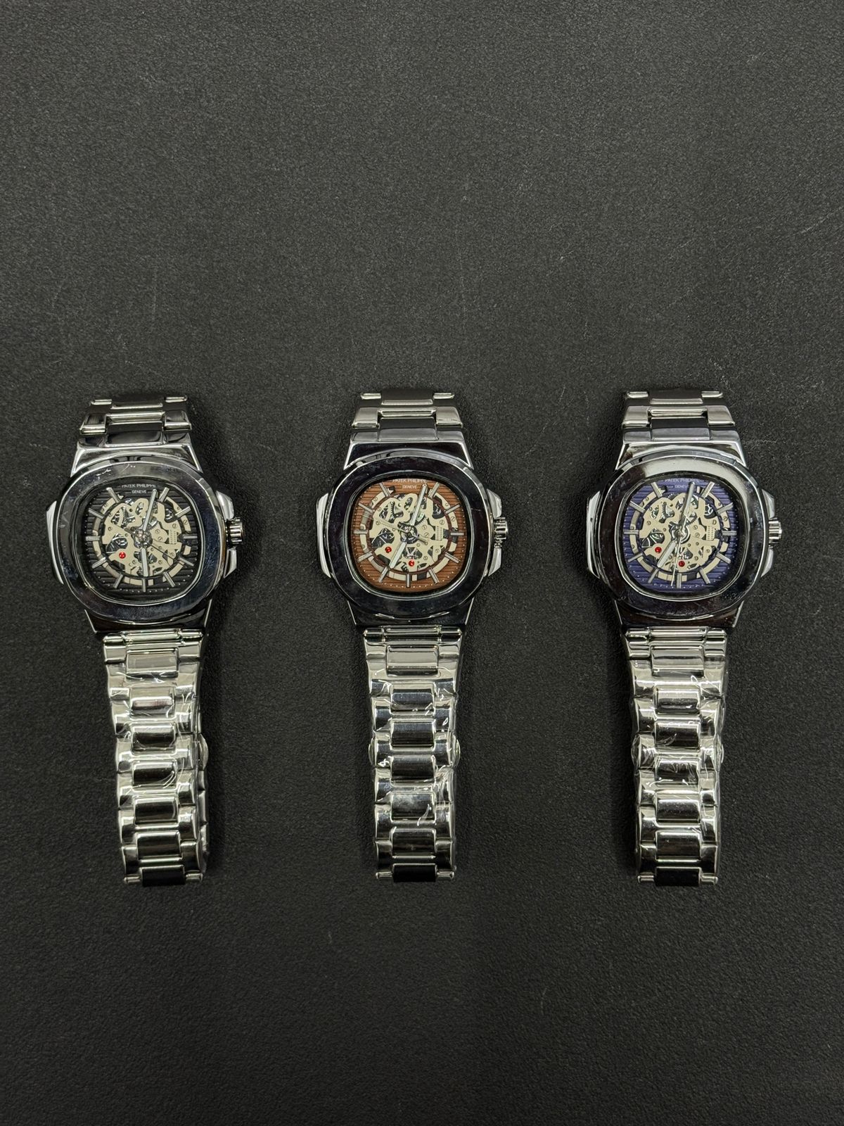 Replica watch collection featuring black, brown and blue skeleton dials with stainless steel bracelets, luxury men's wristwatch display