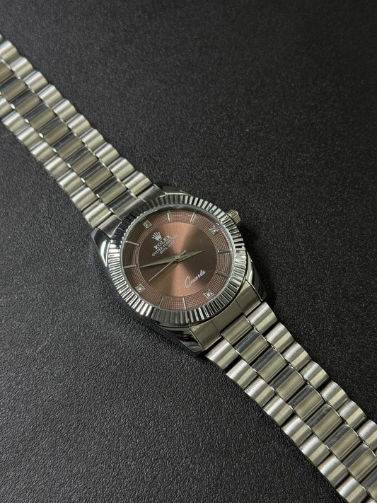 Silver watch with a brown face on a dark textured surface