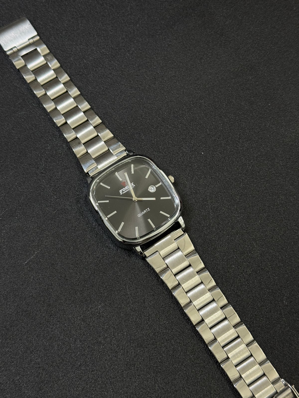Silver wristwatch with a dark face on a black background