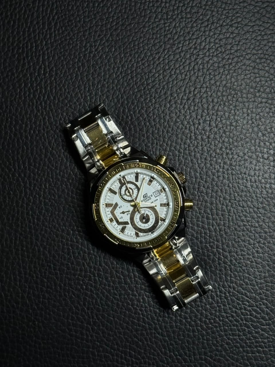 Luxury gold and silver replica watch with white chronograph dial, stainless steel bracelet and date display on black background