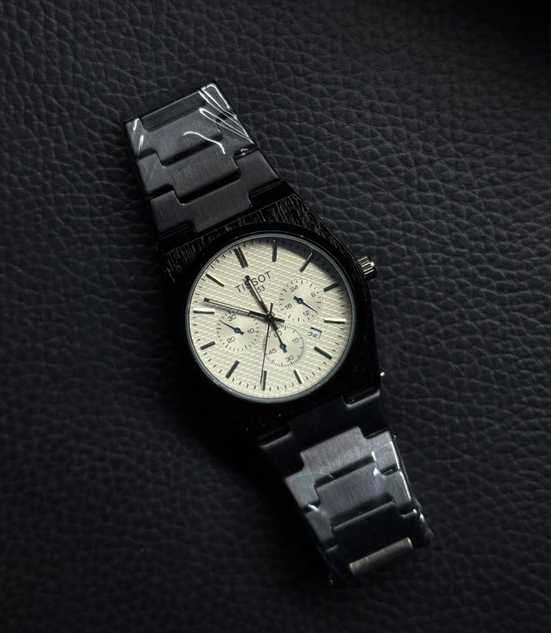 Premium replica watch with black stainless steel bracelet, textured white chronograph-style dial and luxury integrated bracelet design.