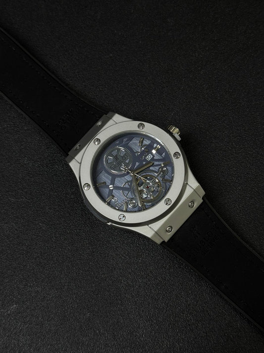 Premium men's replica watch featuring a blue skeleton dial, silver bezel, exposed mechanical design, and black leather-style strap