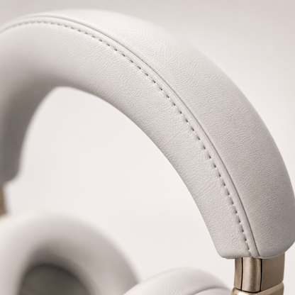 Extreme close-up of the premium padded headband on white over-ear wireless Bluetooth headphones, showcasing soft leather-like cushioning, precision stitching and metallic hinge design.