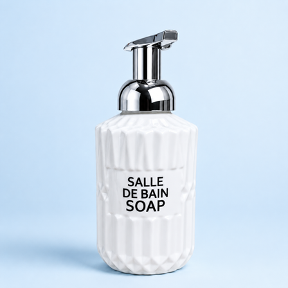 White Ribbed Soap Pump Bottle with chrome dispenser pump, textured ceramic-style body, modern bathroom countertop soap dispenser on light blue background