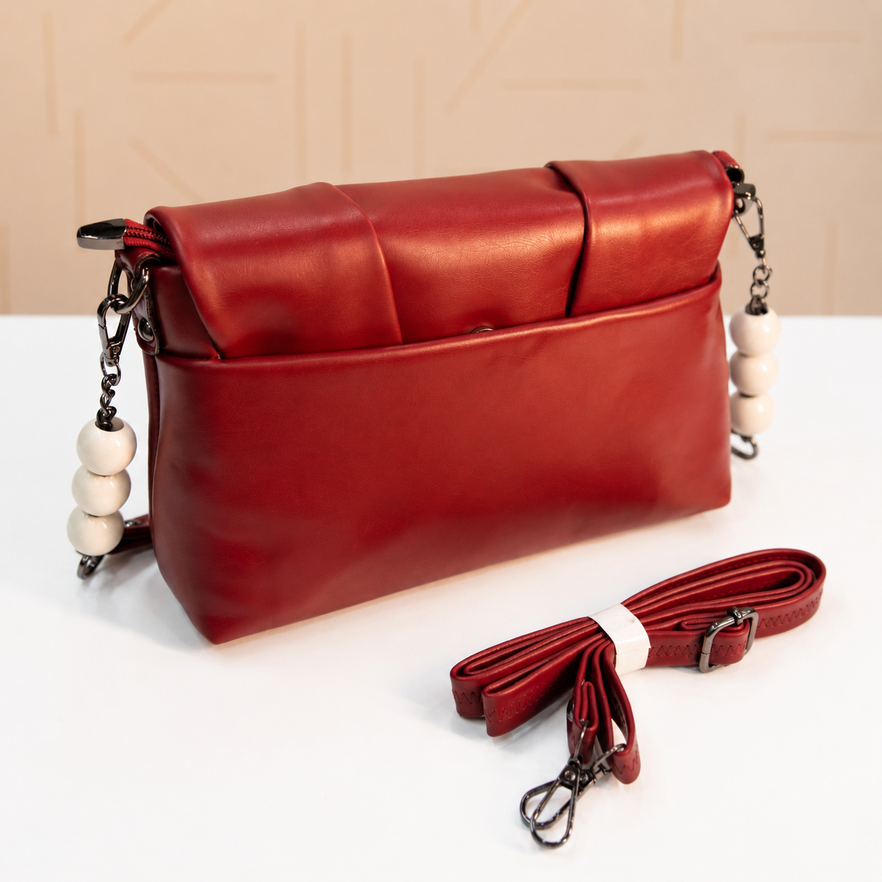 Back view of a premium red women's shoulder bag featuring a smooth leather-look finish, rear slip pocket, decorative white beaded chain accents, and detachable adjustable crossbody strap.