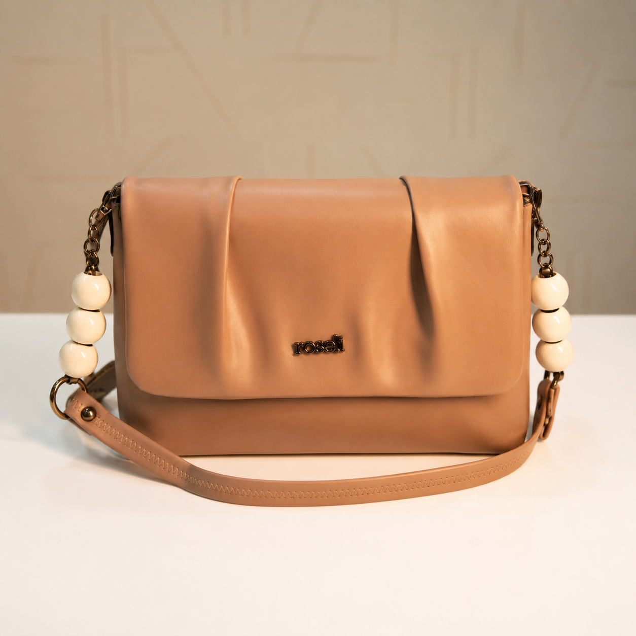 Front view of a nude beige women's shoulder bag featuring a pleated flap design, decorative white beaded chain handles, smooth leather-look finish, and detachable shoulder strap.