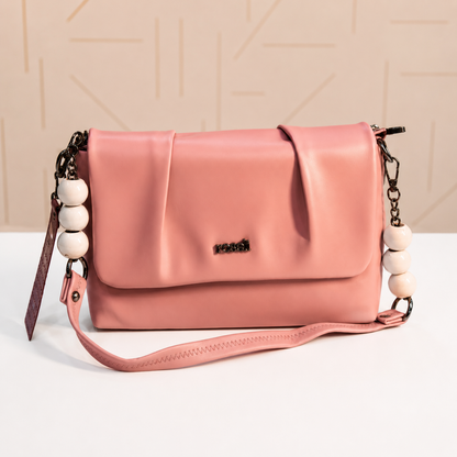 Front view of a blush pink women's shoulder and crossbody bag with a pleated flap, decorative white beaded chain handles, structured silhouette, and adjustable detachable strap.