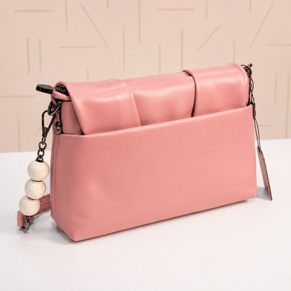 Back view of a blush pink women's shoulder bag featuring a smooth leather-look finish, rear slip pocket, decorative white beaded chain accents, and a detachable adjustable crossbody strap.